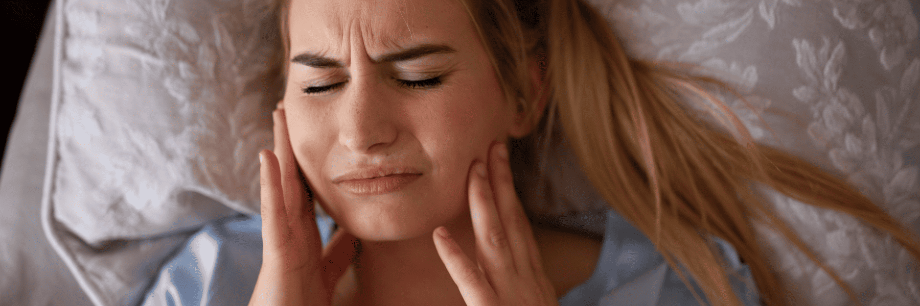 woman with jaw pain from nighttime teeth grinding wearing a custom night guard