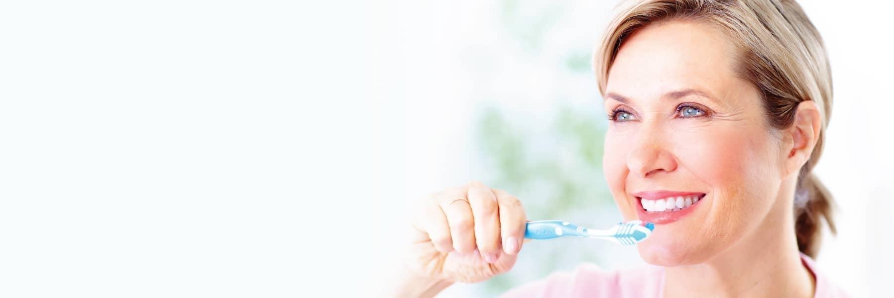 Woman brushing her teeth at dentist in Webster Groves MO