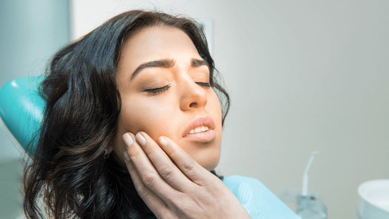 Woman rubbing jaw in pain, symbolizing bruxism issues, for Webster Groves Dental's blog on night gua