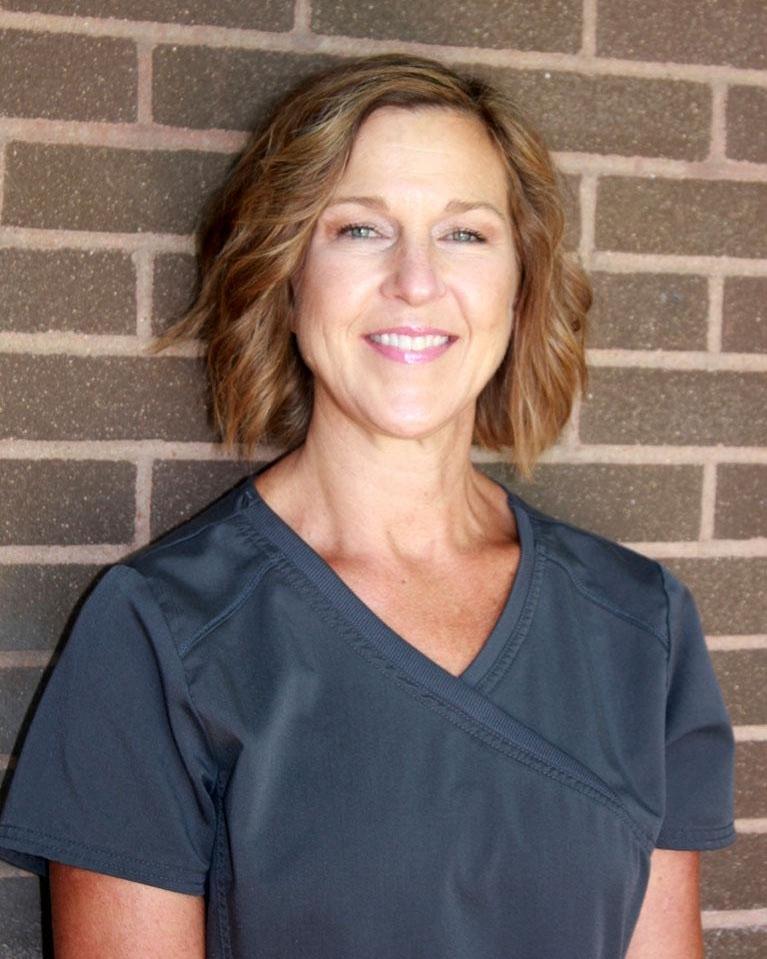 professional headshot of a smiling woman in navy scrubs
